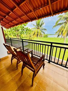 a balcony with a bench and a view of the ocean at Lake View Cottage in Tissamaharama