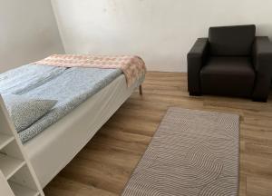 Cama en habitación con silla y alfombra en Vollmers en Malmö