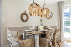 una sala da pranzo con tavolo, sedie e lampadari a braccio di Leevste Suester a Westerland