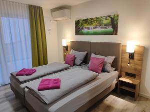 2 camas en una habitación de hotel con almohadas rosas en Hotel Gästehaus Stock Zimmer Wasserfall, en Friedrichshafen