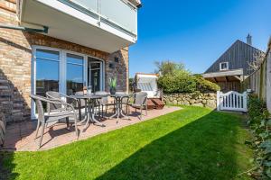 eine Terrasse mit einem Tisch und Stühlen auf einem Rasen in der Unterkunft Alva 1 in Westerland