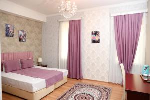 Nemi Hotel Baku في باكو: غرفة نوم بسرير وستائر وردية وثريا