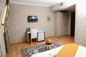 Nemi Hotel Baku في باكو: غرفة نوم بسرير وطاولة ومكتب