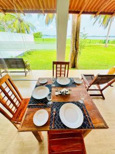 a wooden table with plates on it with chairs and a view of the ocean at Lake View Cottage in Tissamaharama
