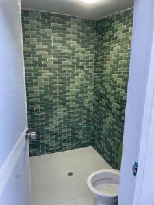 baño con aseo y pared de azulejos verdes en Hammocks - Hamacas en Riohacha