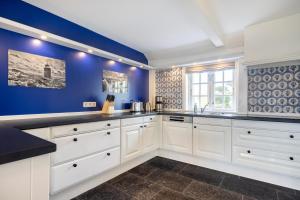 a kitchen with white cabinets and blue walls at Victoria in Keitum +43 photos