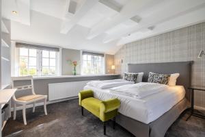 a bedroom with two beds and a yellow chair at Victoria in Keitum