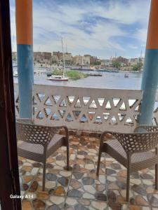 Duas cadeiras numa varanda com vista para a água em NiLe ViEW RANA NUbian Guest HOUES em Aswan