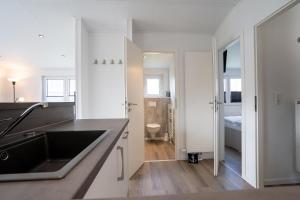 a white kitchen with a sink and a bathroom at Ostseecamp Chalet Haffkrug No 55 in Scharbeutz +22 photos