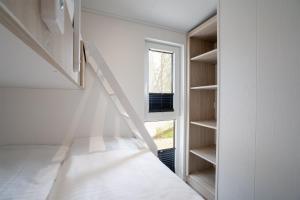 a staircase in a white room with a window at Ostseecamp Chalet Haffkrug No 55 in Scharbeutz