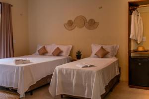 two beds with white sheets in a room at Pousada Rota do Kite Preá in Prea