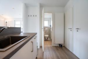 a white kitchen with a sink and a toilet at Ostseecamp Chalet Haffkrug No 59 in Scharbeutz +22 photos