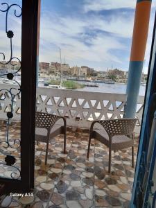 a balcony with two chairs and a view of the water at NiLe ViEW RANA NUbian Guest HOUES in Aswan