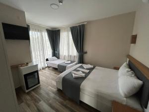 ein Hotelzimmer mit 2 Betten und einem TV in der Unterkunft AURORA SIĞACIK HOTEL in Seferihisar