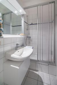 een witte badkamer met een wastafel en een douche bij Strandkorb in der Villa Medici in Norderney