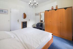 a bedroom with a large bed and a wooden cabinet at Strandkorb in der Villa Medici in Norderney