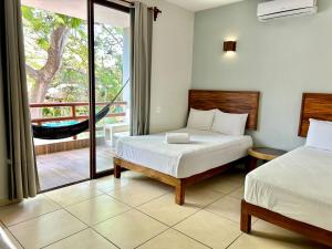 a bedroom with two beds and a balcony with a hammock at Hotel Aldea Sol in Zihuatanejo +38 photos