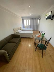 uma sala de estar com um sofá, uma cama e uma mesa em Harbor Self Buriti Hotel em Campo Grande