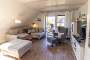 uma sala de estar com um sofá e uma televisão em Wandalennest em Greetsiel