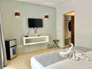 una camera con TV e un cigno su un letto di Hotel Aldea Sol a Zihuatanejo