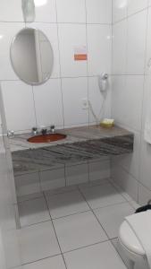 a bathroom with a sink and a mirror and a toilet at Harbor Querência Hotel in Cascavel