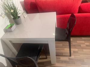 a white table with two chairs and a red couch at gemütliches Einliegerapartment, 50 qm in Trippstadt