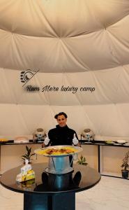 Rum Mere luxury camp في وادي رم: رجل يقف خلف طاولة مع صينية من الطعام