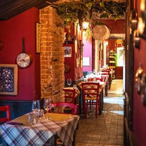 una fila di tavoli in un ristorante con pareti rosse di Palazzo Bellezia Luxury Suites a Torino