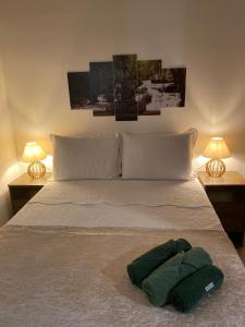 Una cama con dos lámparas y una toalla verde. en Chalé Capão Vibes en Vale do Capao