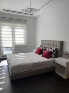 een witte slaapkamer met een groot bed met rode kussens bij La Remaz 35 in El Jadida