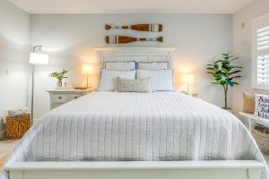 a white bedroom with a white bed with blue pillows at Fort Pierce Condo with Screened Porch Walk to Beach in Fort Pierce +22 photos