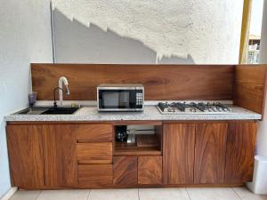 um balcão de cozinha com um micro-ondas e um lavatório em Hotel Aldea Sol em Zihuatanejo