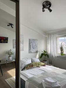 a white bedroom with a bed and a window at VesiLahti RoofLevel Apartment in Lahti