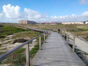 eine hölzerne Promenade über einem Strand mit Gebäuden im Hintergrund in der Unterkunft DORIS Beach House. Praia Furadouro .Ovar.Aveiro in Furadouro