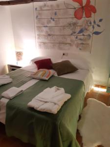 Un dormitorio con una cama verde con toallas. en Musas Gastro Casa Rural, en Valdealgorfa