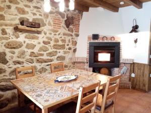 a dining room with a table and a stone fireplace at La torna in Navarredonda de Gredos