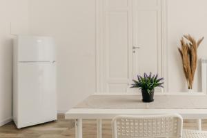 a white kitchen with a table and a white refrigerator at Sofia's Central Apartment Palermo in Palermo