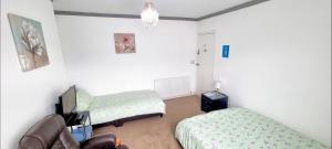 Zimmer mit 2 Betten, einem Stuhl und einem TV in der Unterkunft Plymouth Airbnb in Plymouth