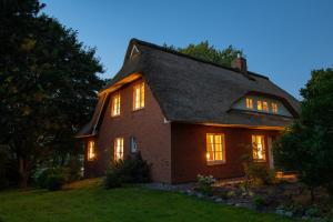 a house with its lights on in the yard at Reetdachhaus direkt am Wasser in Breiholz