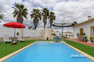 a swimming pool in a yard with two umbrellas at Casinha Branca in Fundão