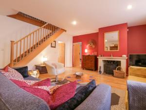 ein Wohnzimmer mit einem Sofa und einer Treppe in der Unterkunft Lime Tree Cottage, Blythburgh in Halesworth