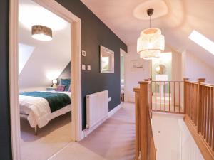 ein Schlafzimmer mit einem Bett und einen Flur mit einer Treppe in der Unterkunft Lime Tree Cottage, Blythburgh in Halesworth