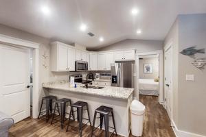 a kitchen with white cabinets and bar stools at Beach Cottage South in Dauphin Island