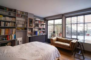 Loft avec terrasses en plein Paris في باريس: غرفة نوم بسرير وكرسي وارفف كتب