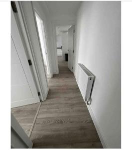 um corredor vazio com paredes brancas e pisos de madeira em Morden 2 bed central em Hendon