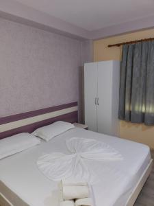 a bedroom with a white bed with two towels on it at Vila Green Relax in Vlorë