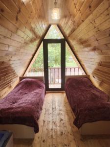 due letti in una camera da letto soppalcata con una grande finestra di A-frame a Vǝndam