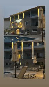 a pool with chairs and umbrellas in front of a building at 3 Island View Hotel in Nydri