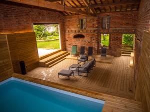 a room with a swimming pool and a patio with chairs at le gîte du soleil in Lézat-sur-Lèze