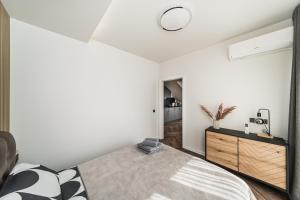 a bedroom with a bed and a wooden dresser at Riverra House - Panorama View Apartment in Kaunas